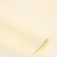 Gros plan sur des feuilles superposées de Popeline polyester-coton au mètre de Longan Craft France, un tissu doux et respirant de couleur jaune pâle, idéal pour les robes, les chemises et les nappes sans texte ni marquage visible.
