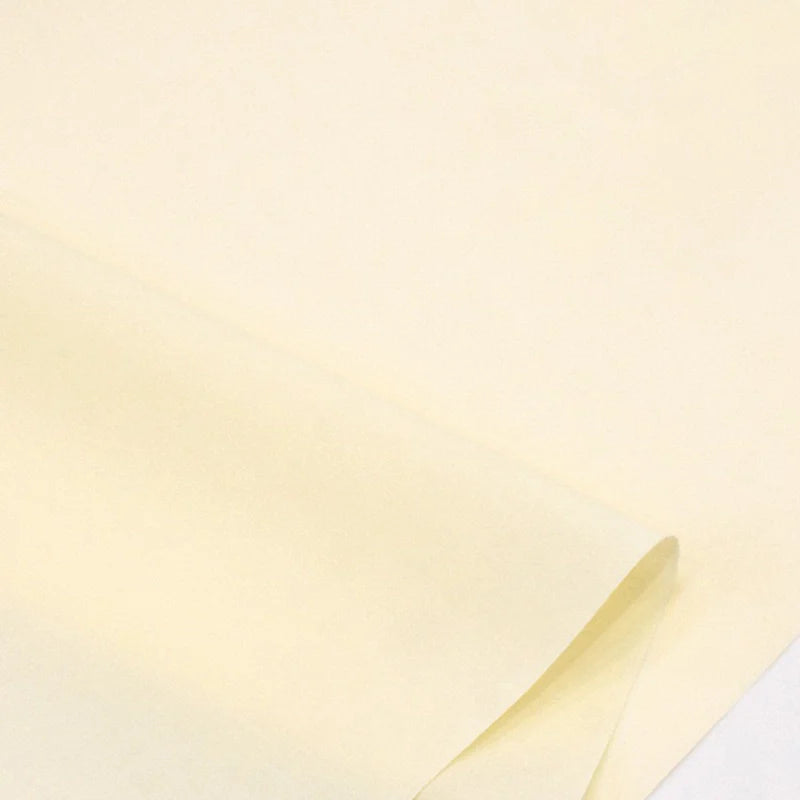 Gros plan sur des feuilles superposées de Popeline polyester-coton au mètre de Longan Craft France, un tissu doux et respirant de couleur jaune pâle, idéal pour les robes, les chemises et les nappes sans texte ni marquage visible.