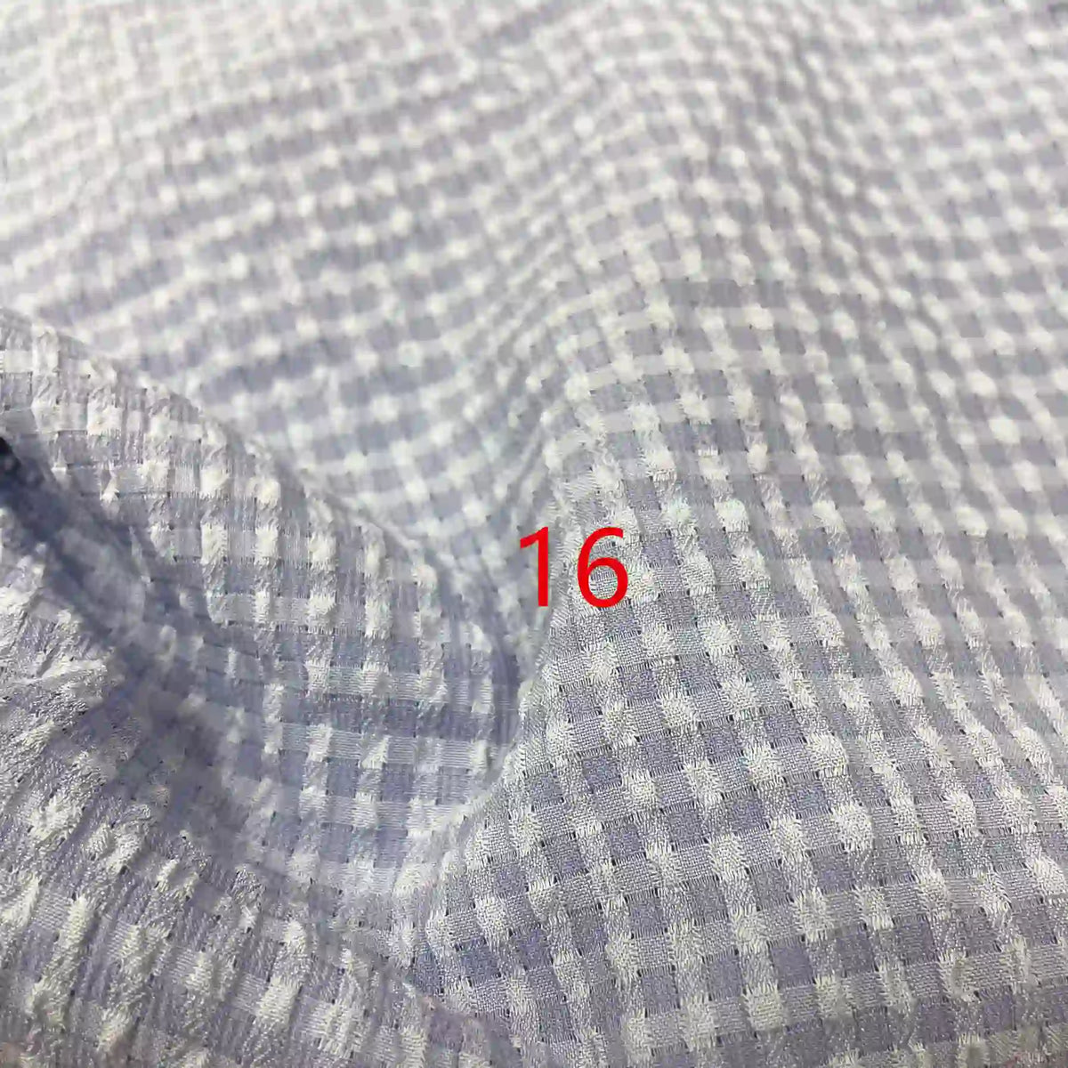 Gros plan sur le polyester Seersucker à carreaux vichy au mètre de Longan Craft France, à carreaux gris clair et blancs avec le chiffre 16 en rouge au centre.