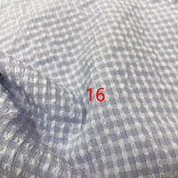 Gros plan sur le polyester Seersucker à carreaux vichy au mètre de Longan Craft France, à carreaux gris clair et blancs avec le chiffre 16 en rouge au centre.