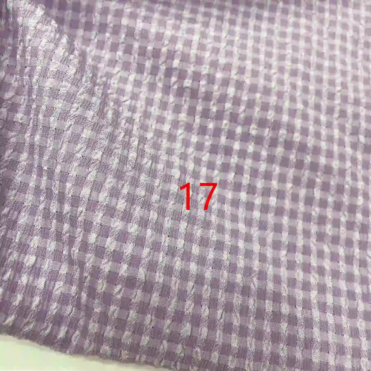 Gros plan sur le tissu seersucker polyester à carreaux vichy au mètre de Longan Craft France, violet et blanc, avec le chiffre 17 en rouge près du centre.