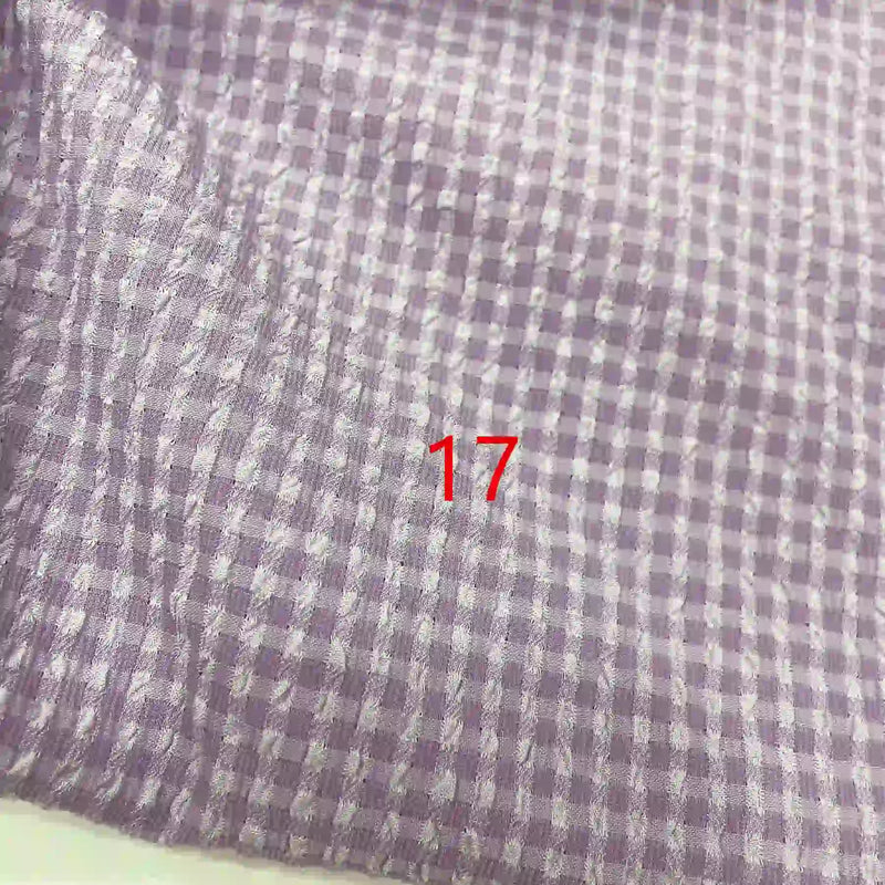 Gros plan sur le tissu seersucker polyester à carreaux vichy au mètre de Longan Craft France, violet et blanc, avec le chiffre 17 en rouge près du centre.