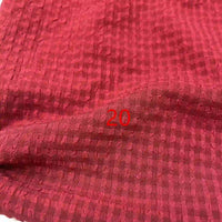 Un gros plan du Seersucker polyester à carreaux vichy au mètre de Longan Craft France montre un tissu texturé rouge froissé avec un motif à carreaux subtil et le nombre "20" imprimé en rouge au centre.