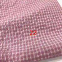 Gros plan sur le tissu Longan Craft France Seersucker polyester à carreaux vichy au mètre, rose et blanc, à l'aspect texturé, avec le chiffre 22 en rouge au centre.