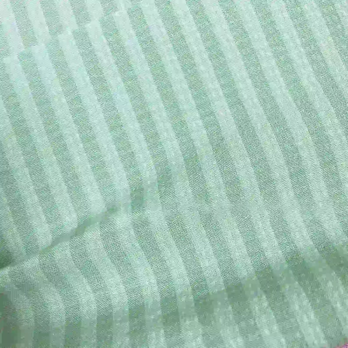 Un gros plan du Seersucker à larges rayures au mètre de Longan Craft France montre un seersucker en polyester vert clair avec des rayures plus claires régulièrement espacées, offrant un aspect doux et texturé - idéal pour la décoration intérieure ou les chemises vintage.