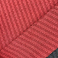 Gros plan sur le Seersucker à larges rayures au mètre de Longan Craft France en rouge, avec des rayures diagonales rouge foncé. Le tissu seersucker léger est plié, avec un soupçon de gris foncé visible dans le coin inférieur droit.