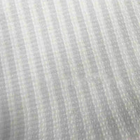 Gros plan sur le Seersucker à larges rayures au mètre de Longan Craft France, un polyester seersucker gris clair avec des rayures verticales légèrement translucides et un motif texturé subtil - tissu vintage idéal pour les chemises ou la décoration intérieure.