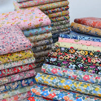 Les piles de Tissu popeline de coton imprimé au mètre de Longan Craft France, qui présentent des motifs floraux 100 % coton dans des tons vifs et pastel, sont bien rangées - idéales pour le bricolage, le quilting, les nappes, les robes et les chemises.