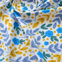 Un gros plan de Tissu popeline de coton imprimé au mètre par Longan Craft France, 100% coton 40S, à motifs floraux bleus et jaunes sur fond blanc, légèrement plissé-idéal pour DIY, quilting, nappes, robes et chemises.