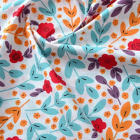 Un gros plan du Tissu popeline de coton imprimé au mètre par Longan Craft France montre des motifs floraux avec des fleurs rouges, orange et jaunes, des feuilles sarcelles et violettes sur fond blanc. Le tissu 100 % coton est légèrement froncé, ce qui crée des plis doux, parfaits pour les projets de bricolage ou d'habillement.