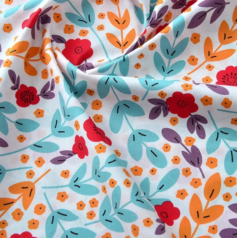 Un gros plan du Tissu popeline de coton imprimé au mètre par Longan Craft France montre des motifs floraux avec des fleurs rouges, orange et jaunes, des feuilles sarcelles et violettes sur fond blanc. Le tissu 100 % coton est légèrement froncé, ce qui crée des plis doux, parfaits pour les projets de bricolage ou d'habillement.