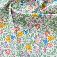 Découvrez le tissu popeline de coton imprimé au mètre, unie 40S 100% coton, à motifs floraux roses, jaunes et verts avec petits lapins bleus. Idéal pour DIY, quilting, nappes, robes et chemises.