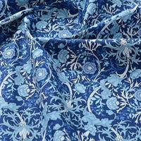 Un gros plan du Tissu popeline de coton imprimé au mètre de Longan Craft France révèle un motif floral bleu et blanc détaillé. Le tissu 100% coton légèrement froissé ajoute une texture riche, parfaite pour le bricolage, le quilting, les peignoirs, les chemises et les langes.