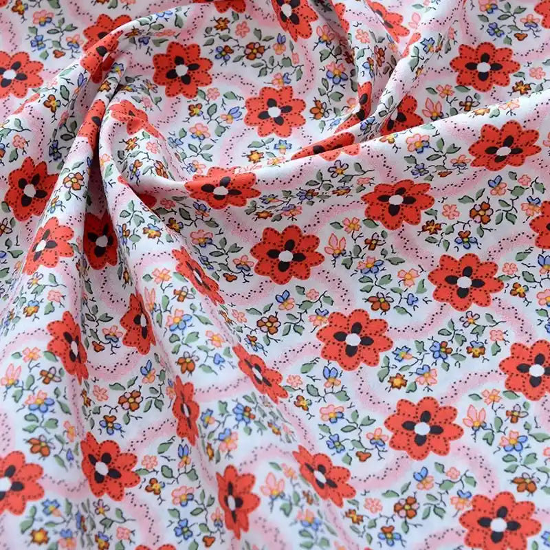 Découvrez de près le tissu popeline de coton imprimé au mètre Longan Craft France : 100 % coton, motifs floraux rouges et multicolores sur fond blanc, doux et souple, idéal pour DIY, quilting, nappes, robes et chemises.