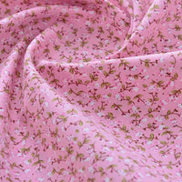 Gros plan sur le tissu popeline de coton imprimé au mètre de Longan Craft France, unie 40S 100% coton à motifs floraux, avec de petites branches vertes et fleurs rose et blanc, parfait pour DIY, quilting, nappes, robes ou chemises.