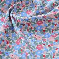 Un gros plan de Longan Craft France Tissu popeline de coton imprimé au mètre, 100% coton 40S à motifs floraux colorés sur fond clair, idéal pour DIY, quilting, nappes, robes et chemises. Sa texture légèrement froissée met en valeur son drapé élégant.