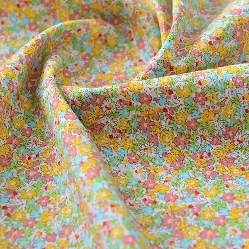 Un gros plan du tissu popeline de coton imprimé au mètre de Longan Craft France montre son motif floral coloré et sa texture douce, idéal pour DIY, quilting, nappes, robes et chemises.