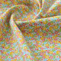 Un gros plan du tissu popeline de coton imprimé au mètre de Longan Craft France montre son motif floral coloré et sa texture douce, idéal pour DIY, quilting, nappes, robes et chemises.