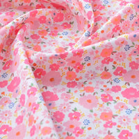 Un gros plan du tissu popeline de coton imprimé au mètre de Longan Craft France, unie 40S 100 % coton, montre un motif floral coloré avec des fleurs roses, orange et violettes sur fond blanc. Idéal pour DIY, quilting, nappes, robes et chemises.