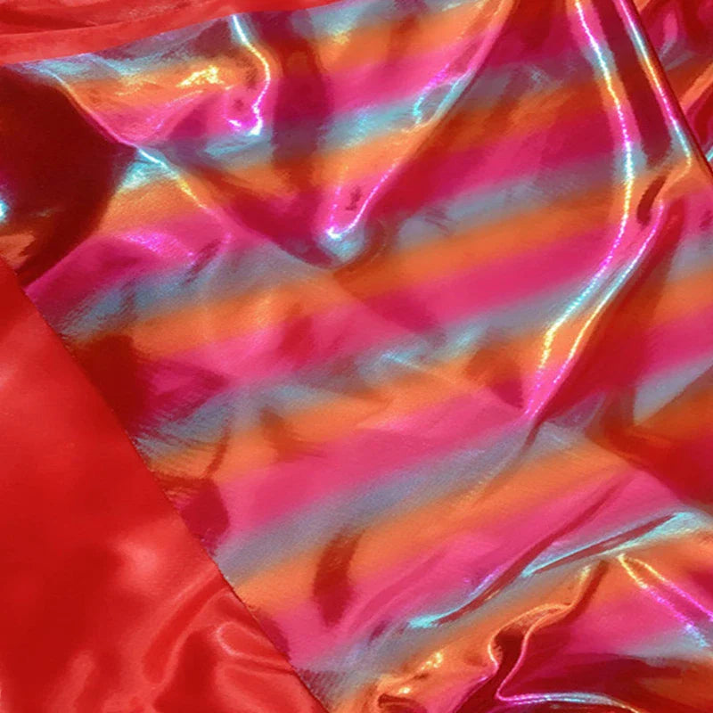 Gros plan sur le Tissu lamé arc-en-ciel au mètre de Longan Craft France, un polyester irisé à rayures dégradées roses, orange, bleues et rouges avec une finition métallique idéale pour costumes de scène ou vêtements spéciaux.