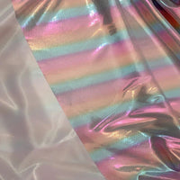 Un tissu lamé arc-en-ciel au mètre de Longan Craft France, en polyester irisé à rayures dégradées, brille à côté d'un tissu blanc uni-idéal pour costumes de scène ou vêtements pour événements spéciaux.