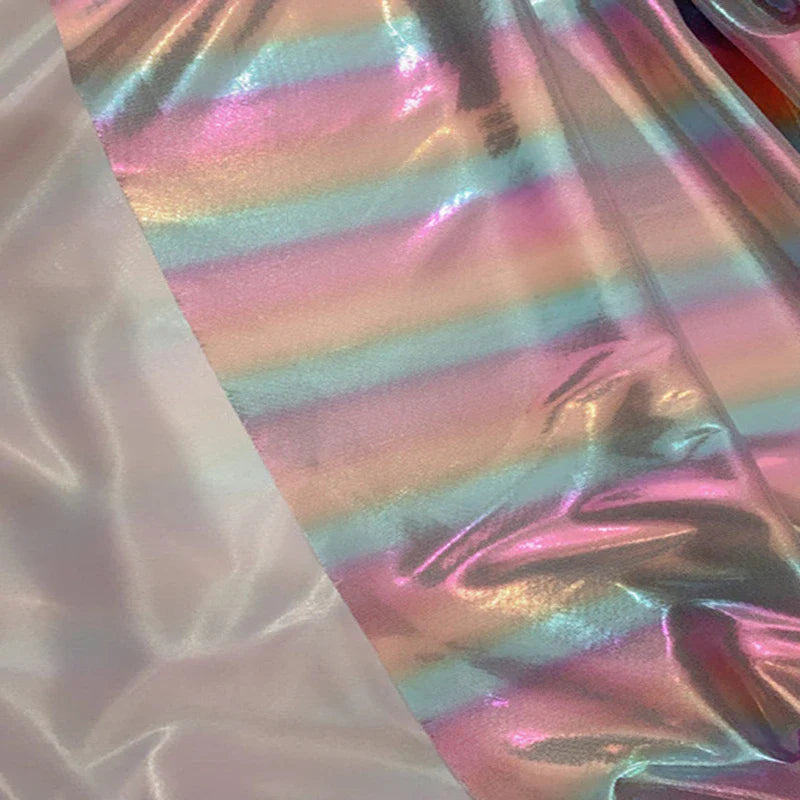 Un tissu lamé arc-en-ciel au mètre de Longan Craft France, en polyester irisé à rayures dégradées, brille à côté d'un tissu blanc uni-idéal pour costumes de scène ou vêtements pour événements spéciaux.