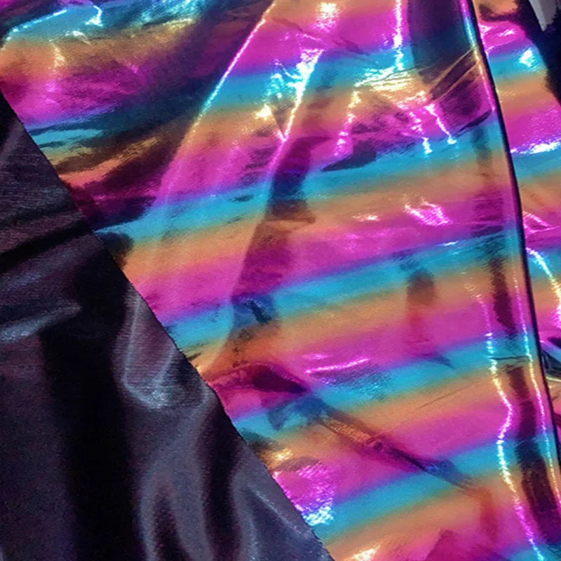 Le tissu lamé arc-en-ciel au mètre de Longan Craft France, en polyester irisé à rayures dégradées roses, orange et bleues avec partie noire, offre une finition métallique idéale pour costumes de scène ou événements spéciaux.