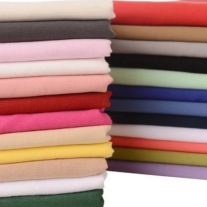 Une pile de "Tissu voile en rayonne au mètre" de Longan Craft France en couleurs unies - blanc, rose, rouge, jaune, vert, bleu, violet et brun -, un tissu léger et respirant destiné à la couture de vêtements ou de linge de maison, est disposée en deux colonnes.