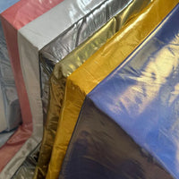 Plusieurs feuilles de Tissu satin lamé au mètre de Longan Craft France en rose, argent, or, jaune et bleu montrent leur éclat métallique - idéal pour les robes DIY, les costumes de scène ou les projets créatifs de couture.
