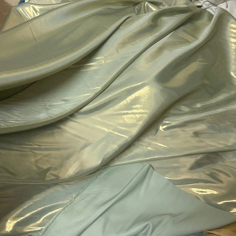 Gros plan sur le Tissu satin lamé au mètre de Longan Craft France, un tissu métallisé en polyester bleu clair brillant avec des plis visibles, parfait pour la couture DIY, les robes de soirée et l'artisanat.