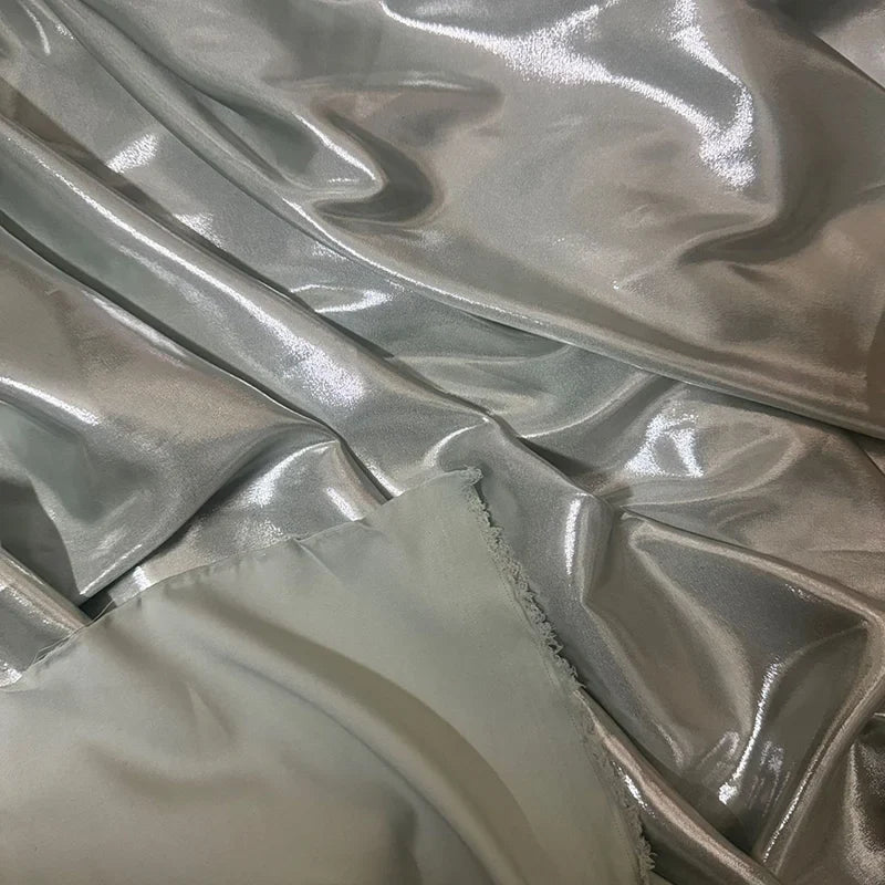 Gros plan sur le satin lamé gris clair brillant de Longan Craft France-Tissu satin lamé au mètre, polyester métallisé et brillant-des plis lisses et un bord non fini, parfaits pour la couture, les robes DIY et la couture créative.