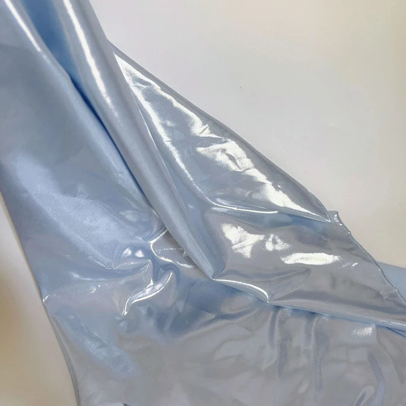 Un morceau de Tissu satin lamé au mètre de Longan Craft France, polyester métallisé et brillant, est drapé sur une surface blanche. Sa finition brillante et son aspect réfléchissant le rendent parfait pour la couture, les peignoirs DIY et les travaux manuels.