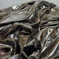 Gros plan sur Longan Craft France Tissu satin lamé au mètre, un tissu polyester métallisé et brillant, parfait pour la couture de robes DIY et travaux manuels, montrant des reflets intenses sur sa texture argentée.