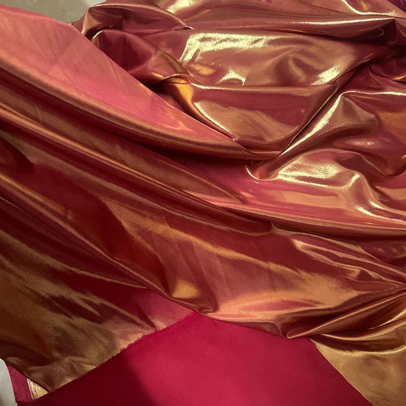 Gros plan sur le Tissu satin lamé au mètre de Longan Craft France, un tissu métallisé en polyester brillant avec des irisations rouges et dorées, idéal pour la couture, les robes DIY et l'artisanat.