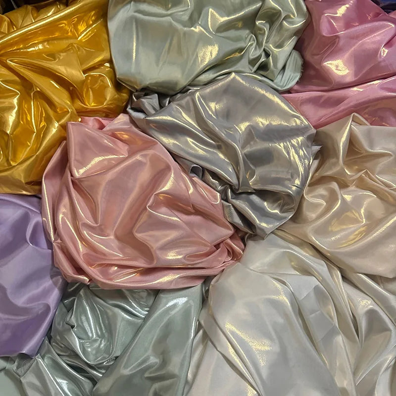 Les tissus satin lamé brillants et froissés de Longan Craft France dans les tons pastel jaune, argent, rose, lavande et crème sont superposés de façon désordonnée. Tissu satin lamé au mètre : polyester métallisé et brillant - idéal pour la couture et les projets de bricolage.