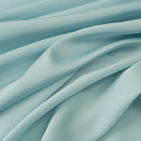 Tissu mousseline satinée au mètre de Longan Craft France, extensible et doux, apparaît en gros plan avec de délicats plis et une texture lisse. Parfait pour une robe soirée élégante ou d'autres vêtements grâce à sa brillance soyeuse.