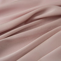 Gros plan sur le tissu mousseline satinée au mètre de Longan Craft France : ce tissu extensible, soyeux et léger présente des plis souples et fluides - idéal pour les soirées en robe de chambre et parfait pour créer de douces ondulations dans vos vêtements.