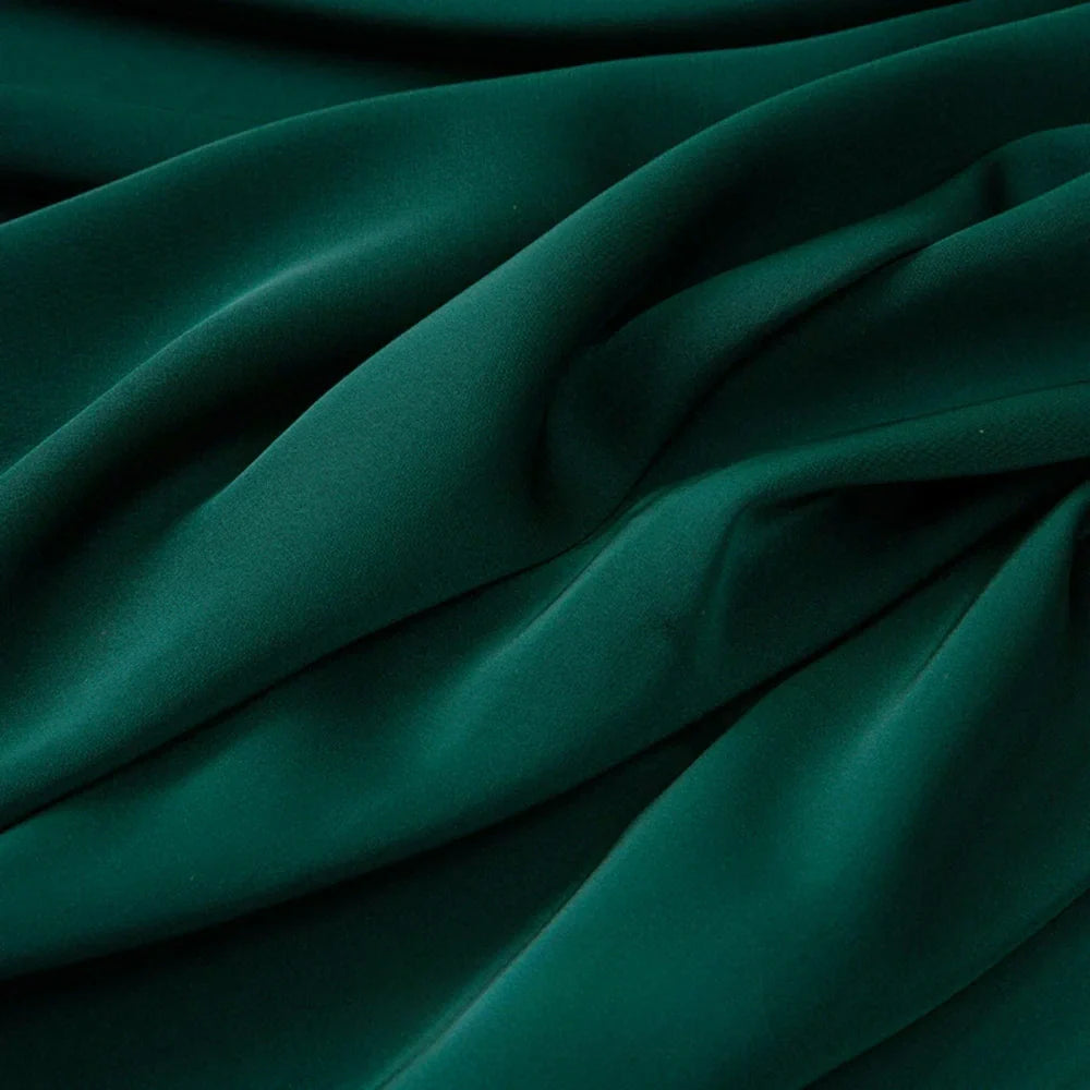 Le Tissu mousseline satinée au mètre de Longan Craft France est un tissu vert foncé, extensible et soyeux, à la texture fluide, parfait pour les vêtements élégants.