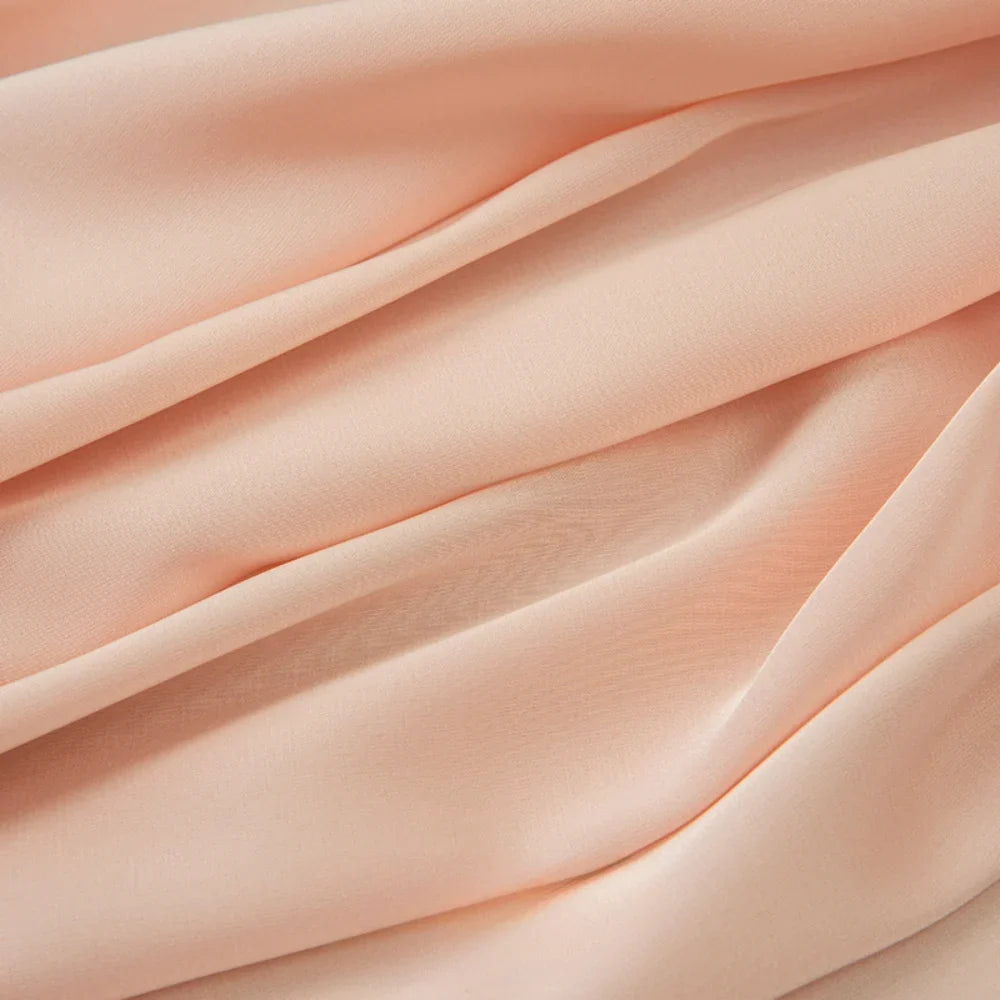 Gros plan sur le tissu mousseline satinée au mètre de Longan Craft France. Ce tissu doux, extensible et légèrement transparent est parfait pour les robes et les vêtements élégants. Mousseline soyeuse, disponible au mètre.