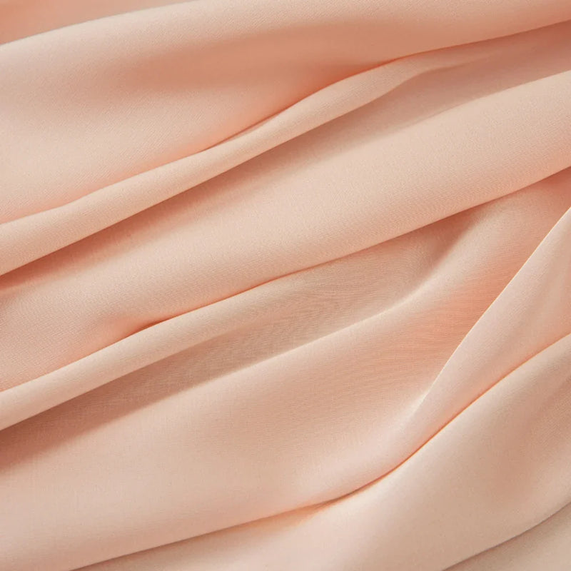 Gros plan sur le tissu mousseline satinée au mètre de Longan Craft France. Ce tissu doux, extensible et légèrement transparent est parfait pour les robes et les vêtements élégants. Mousseline soyeuse, disponible au mètre.