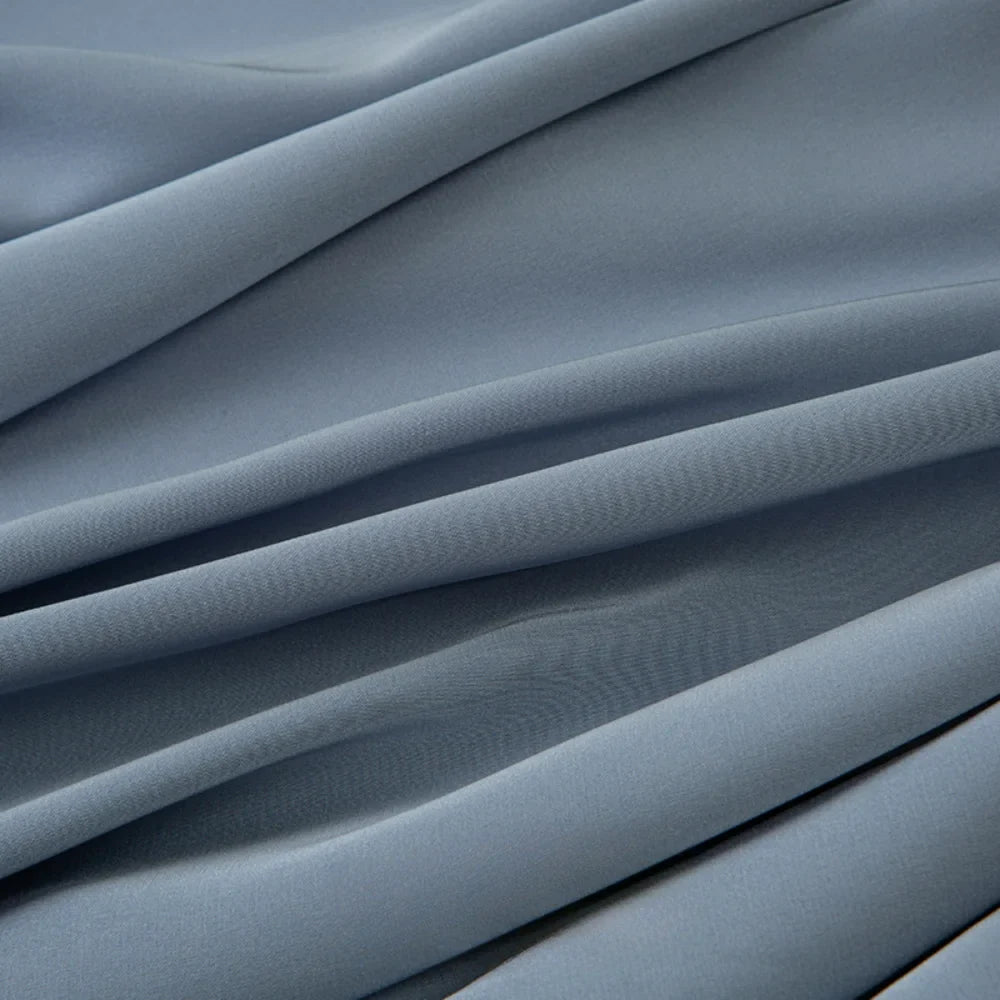 Gros plan sur le Tissu mousseline satiné au mètre, bleu clair et lisse, de Longan Craft France. Ce tissu extensible, doux et soyeux se drape magnifiquement, idéal pour créer des lignes élégantes dans les robes de soirée.