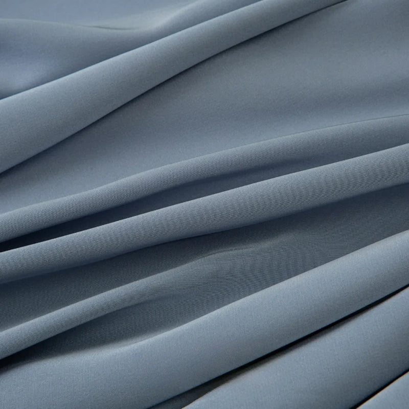 Gros plan sur le Tissu mousseline satiné au mètre, bleu clair et lisse, de Longan Craft France. Ce tissu extensible, doux et soyeux se drape magnifiquement, idéal pour créer des lignes élégantes dans les robes de soirée.