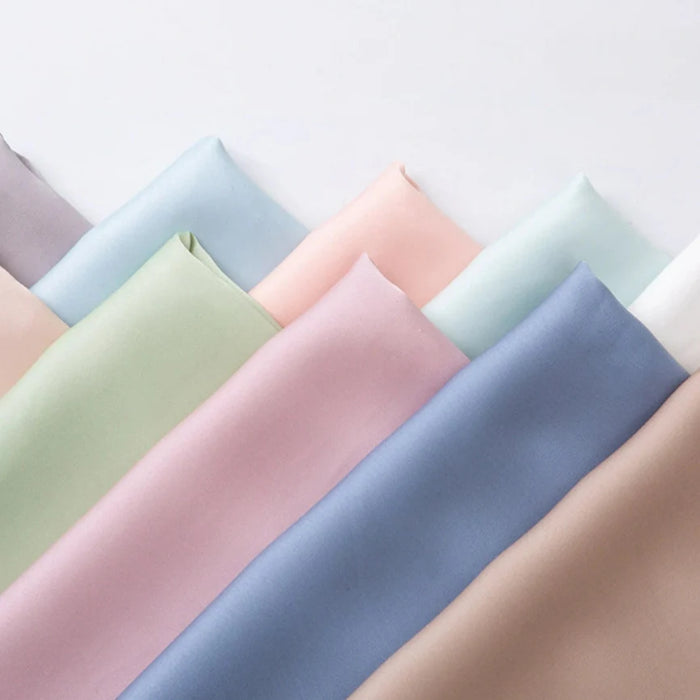 Le Tissu mousseline satinée au mètre-mousseline extensible et douce en rose, vert, bleu, beige, violet et blanc-est élégamment superposée pour des robes de soirée raffinées.