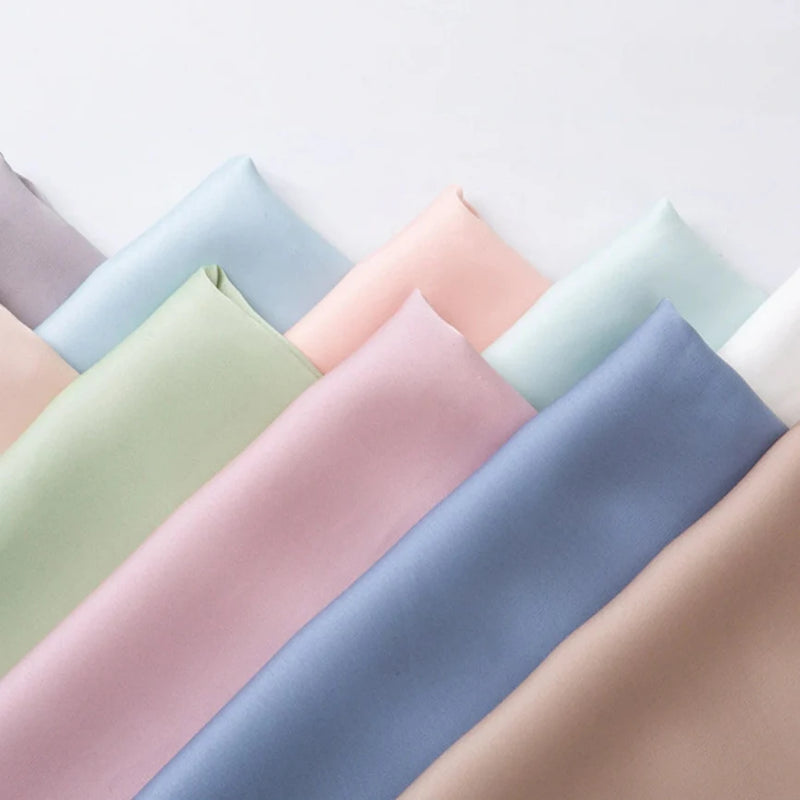 Le Tissu mousseline satinée au mètre-mousseline extensible et douce en rose, vert, bleu, beige, violet et blanc-est élégamment superposée pour des robes de soirée raffinées.