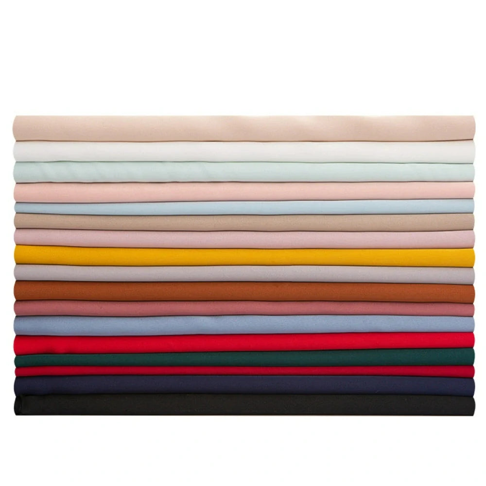Une pile de dix-sept tissus mousseline satinée de Longan Craft France, chacun d'une couleur unie différente, joliment pliés en couches horizontales, des tons neutres clairs en haut aux tons plus foncés en bas. Parfait, extensible et doux comme de la soie pour les projets de vêtements.