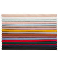 Une pile de dix-sept tissus mousseline satinée de Longan Craft France, chacun d'une couleur unie différente, joliment pliés en couches horizontales, des tons neutres clairs en haut aux tons plus foncés en bas. Parfait, extensible et doux comme de la soie pour les projets de vêtements.