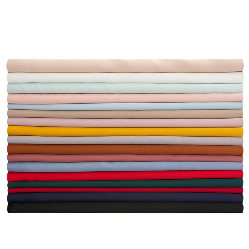 Une pile de dix-sept tissus mousseline satinée de Longan Craft France, chacun d'une couleur unie différente, joliment pliés en couches horizontales, des tons neutres clairs en haut aux tons plus foncés en bas. Parfait, extensible et doux comme de la soie pour les projets de vêtements.