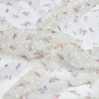 Le Tissu mousseline à petites fleurs de Longan Craft France est un tissu blanc transparent avec de délicats plumetis floraux rose pastel et violet, parfait pour les robes d'été élégantes. Disponible au mètre.