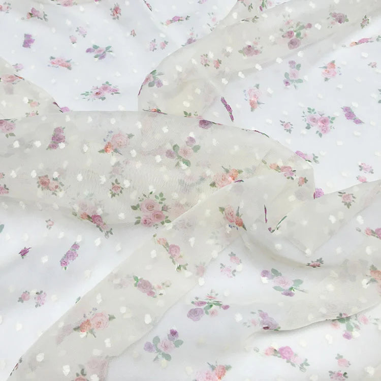 Le Tissu mousseline à petites fleurs de Longan Craft France est un tissu blanc transparent avec de délicats plumetis floraux rose pastel et violet, parfait pour les robes d'été élégantes. Disponible au mètre.