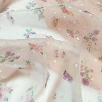 Gros plan sur le tissu mousseline à petites fleurs de Longan Craft France, un tissu transparent et léger à l'imprimé floral délicat de plumetis et de petits points blancs, idéal pour les robes d'été grâce à son drapé doux et à sa texture subtile.